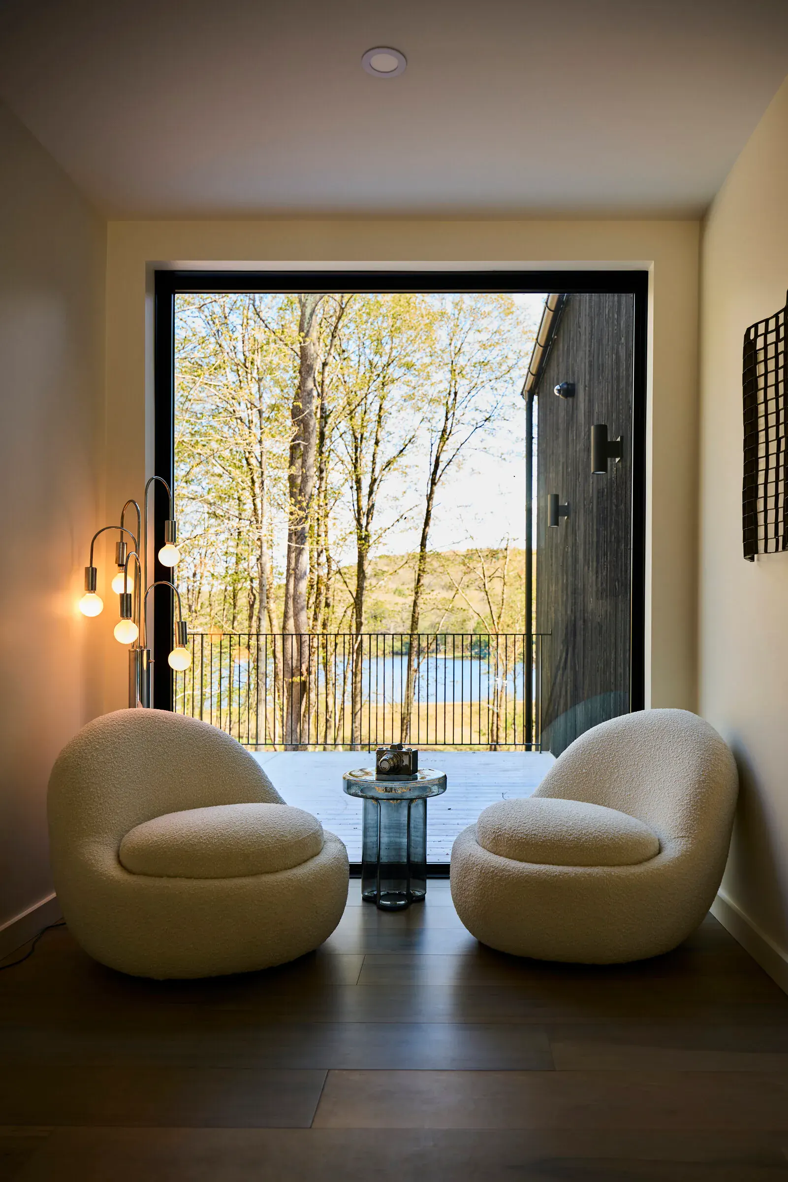 Two boucle lounge chairs facing the lake view window in a Verdant Sound guest bedroom