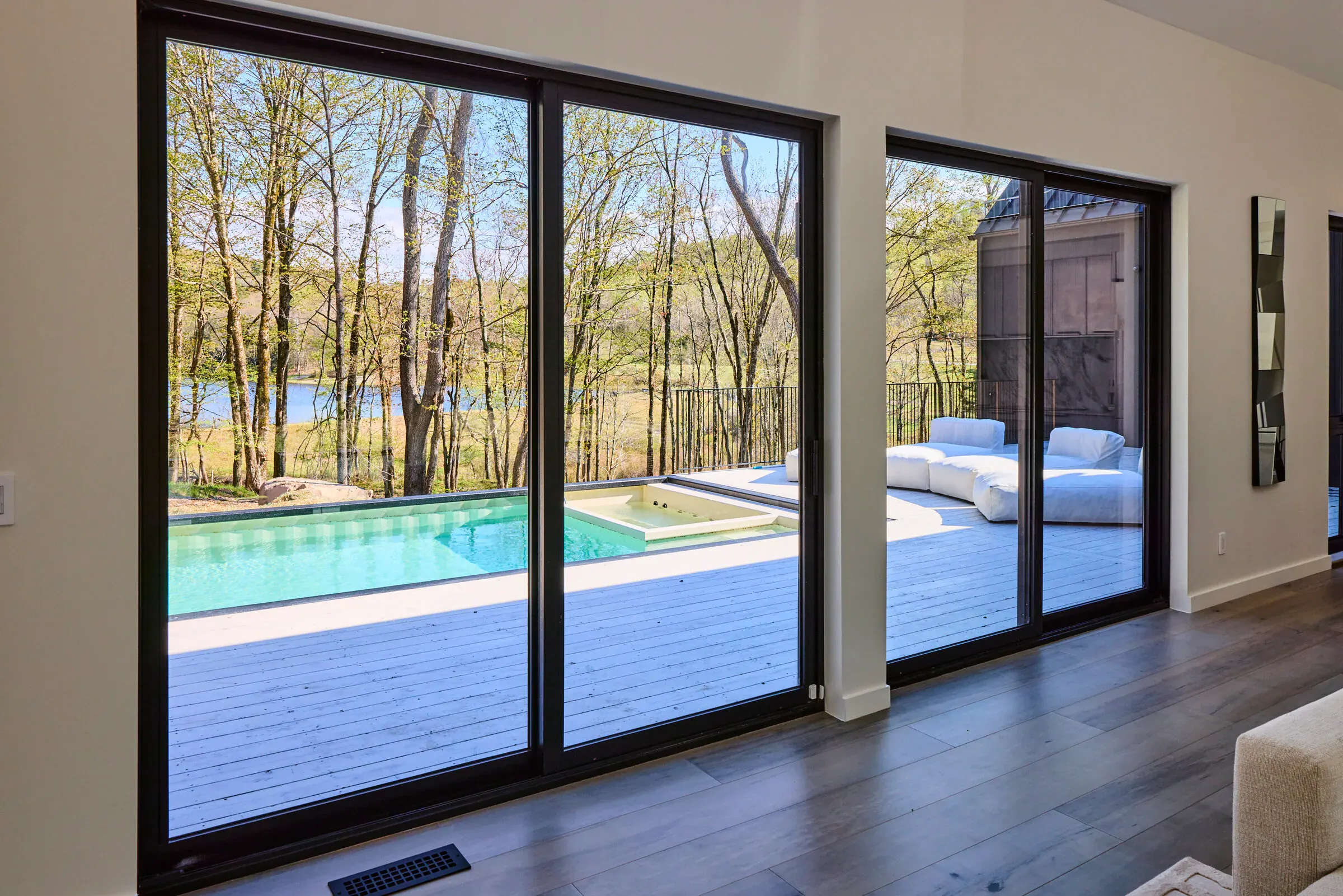 Interior view from Verdant Sound looking out through sliding glass doors to the pool deck and lake
