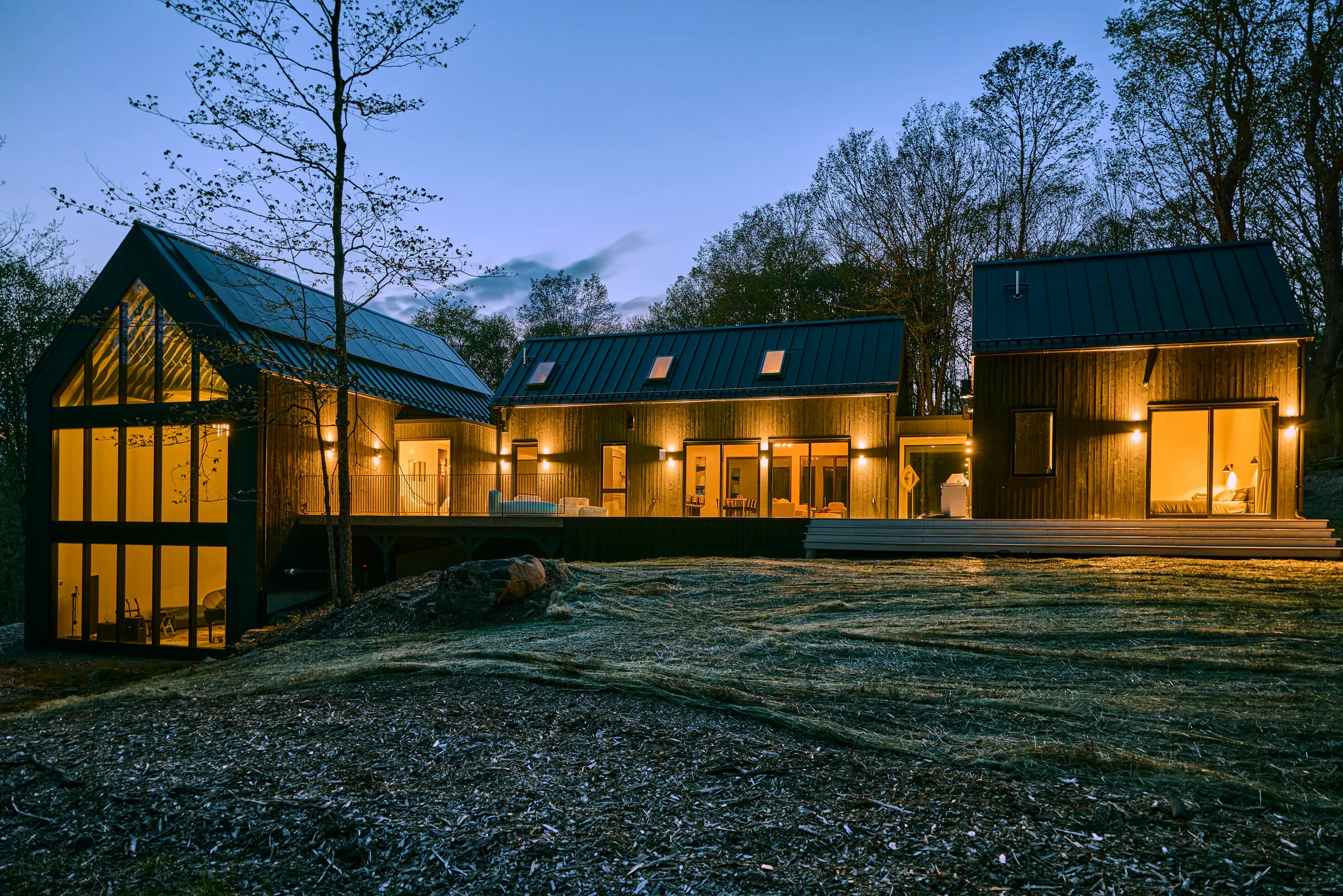 Verdant Sound exterior at blue hour — dark timber cladding and steel roof glowing against the night sky
