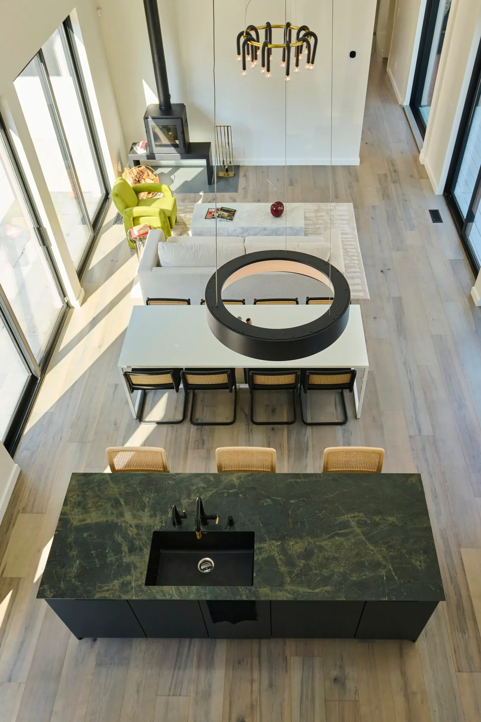 Overhead view of the Verdant Sound kitchen and dining area — green marble island, dining table, wood-burning fireplace