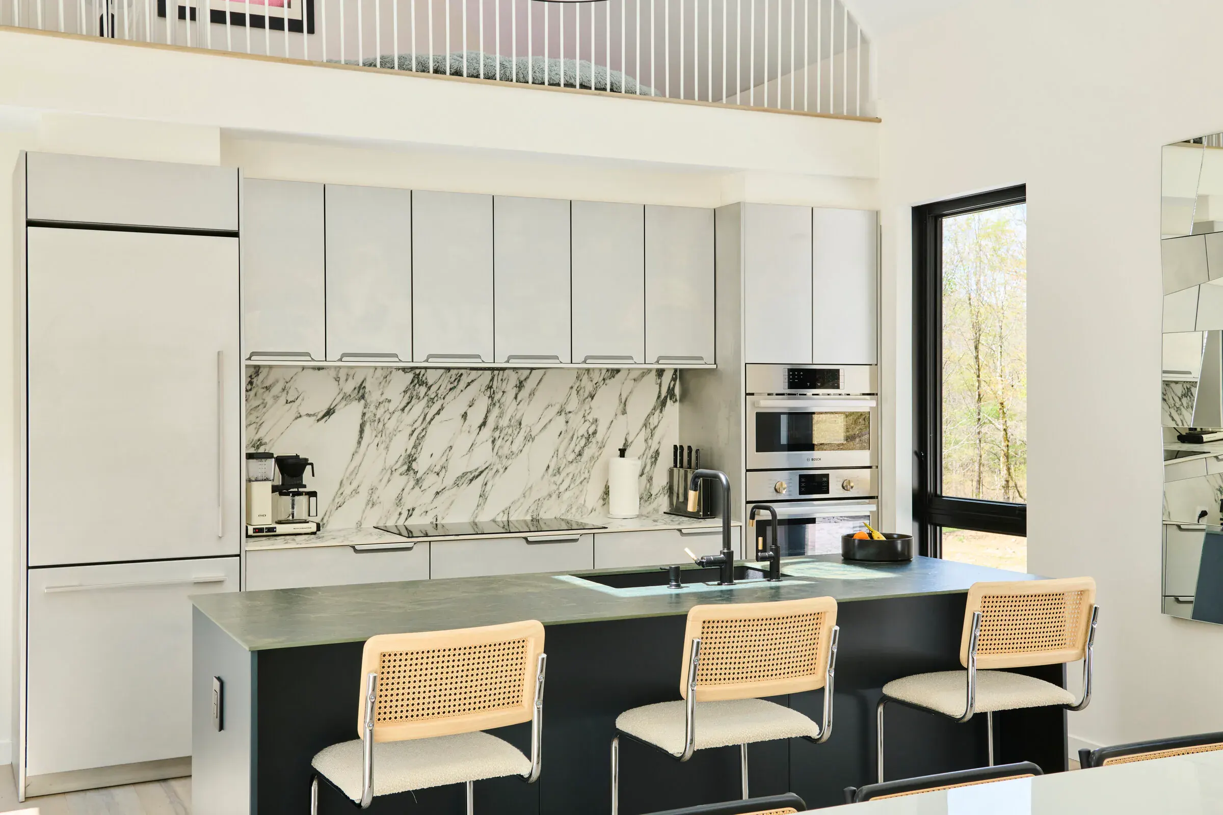 Verdant Sound kitchen — marble backsplash, grey cabinetry, and cane bar stools at the island