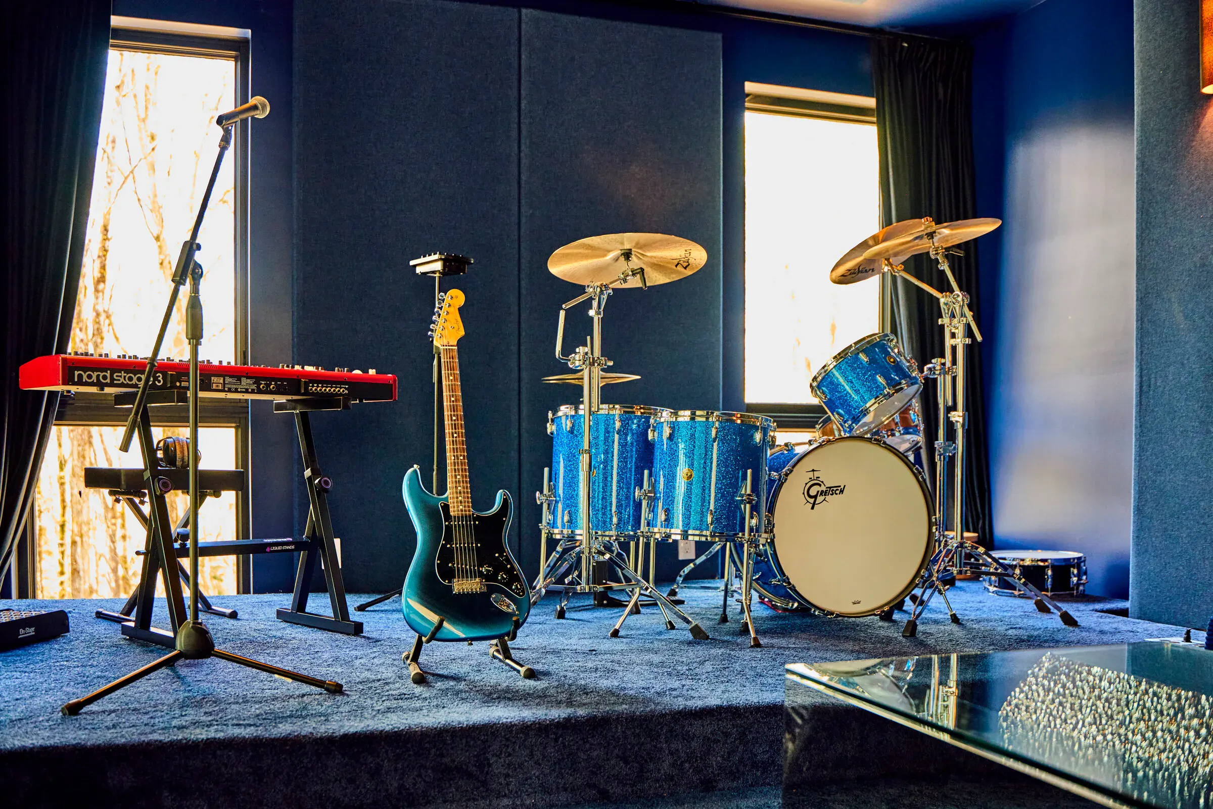 Stage in the Verdant Sound lounge — Gretsch drum kit, Fender Stratocaster, and Nord keyboard